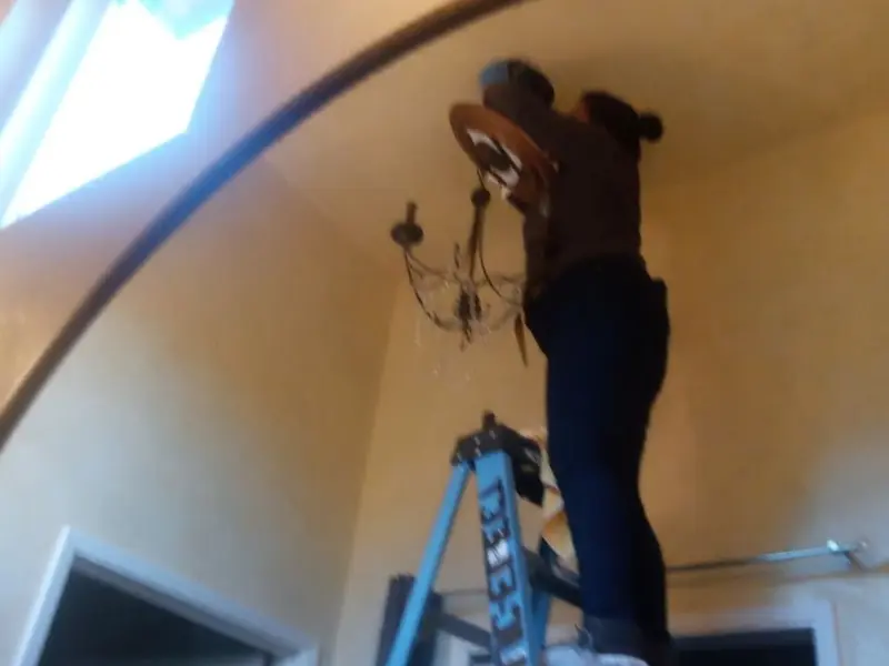 Electrician installing a chandelier in a Bayport residence